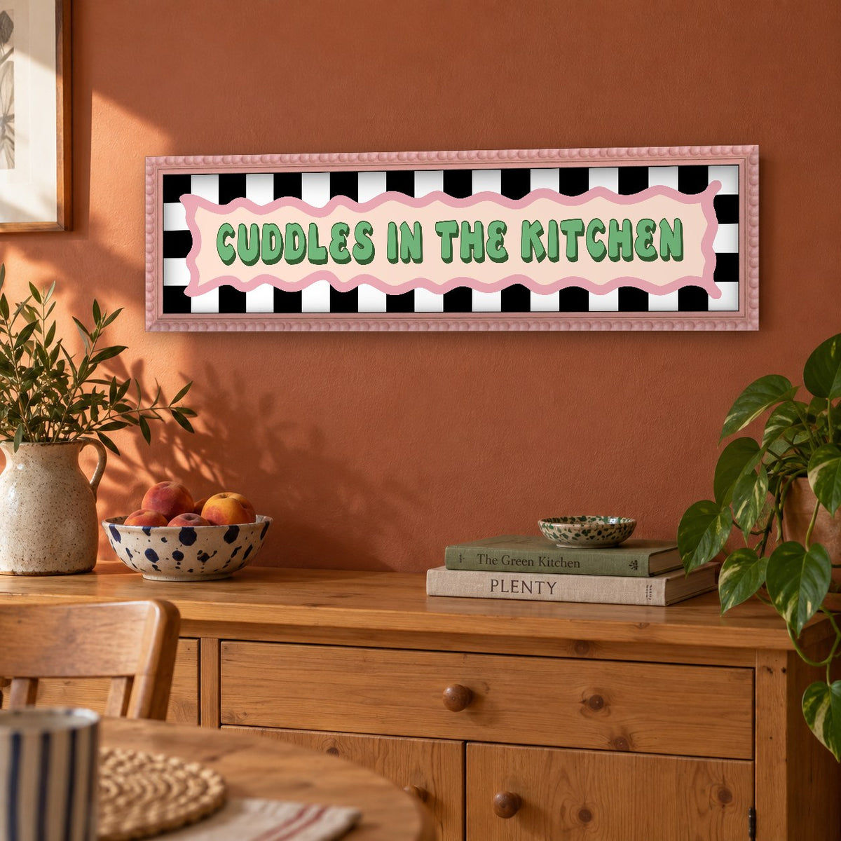 Cuddles In The Kitchen panoramic print in a pink bobbin frame in a room setting